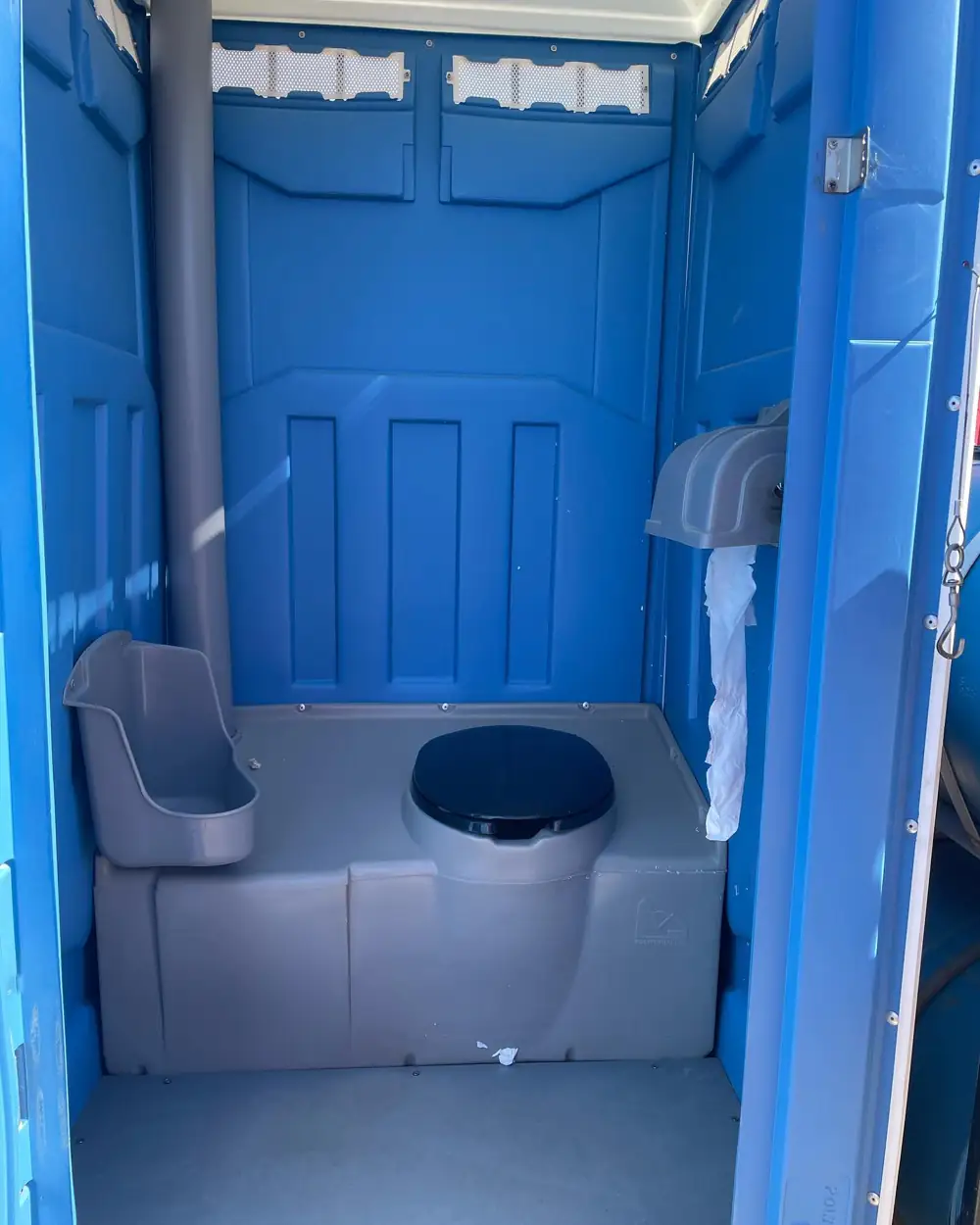 Inside a porta potty showing toilet paper holders