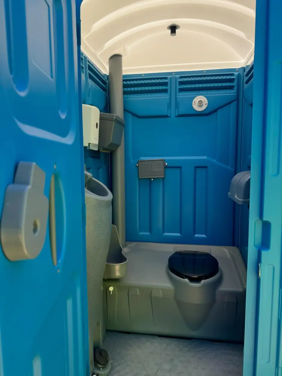 Inside a porta potty showing the vent pipe and seat