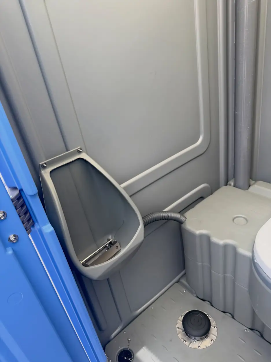 Inside a portable toilet showing the urinal and waste tank
