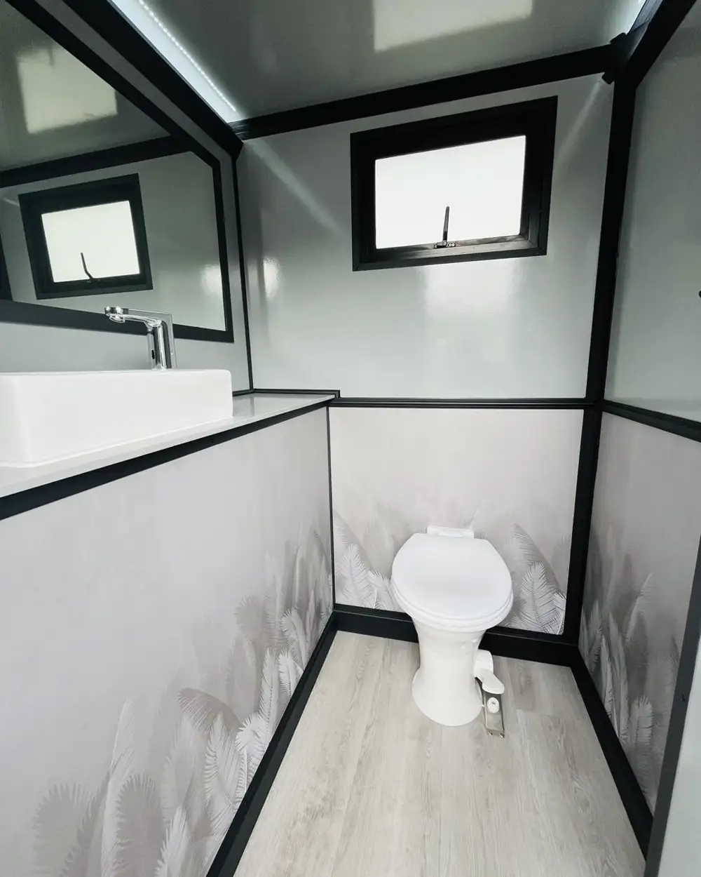 Restroom trailer stall with flushing toilet and window