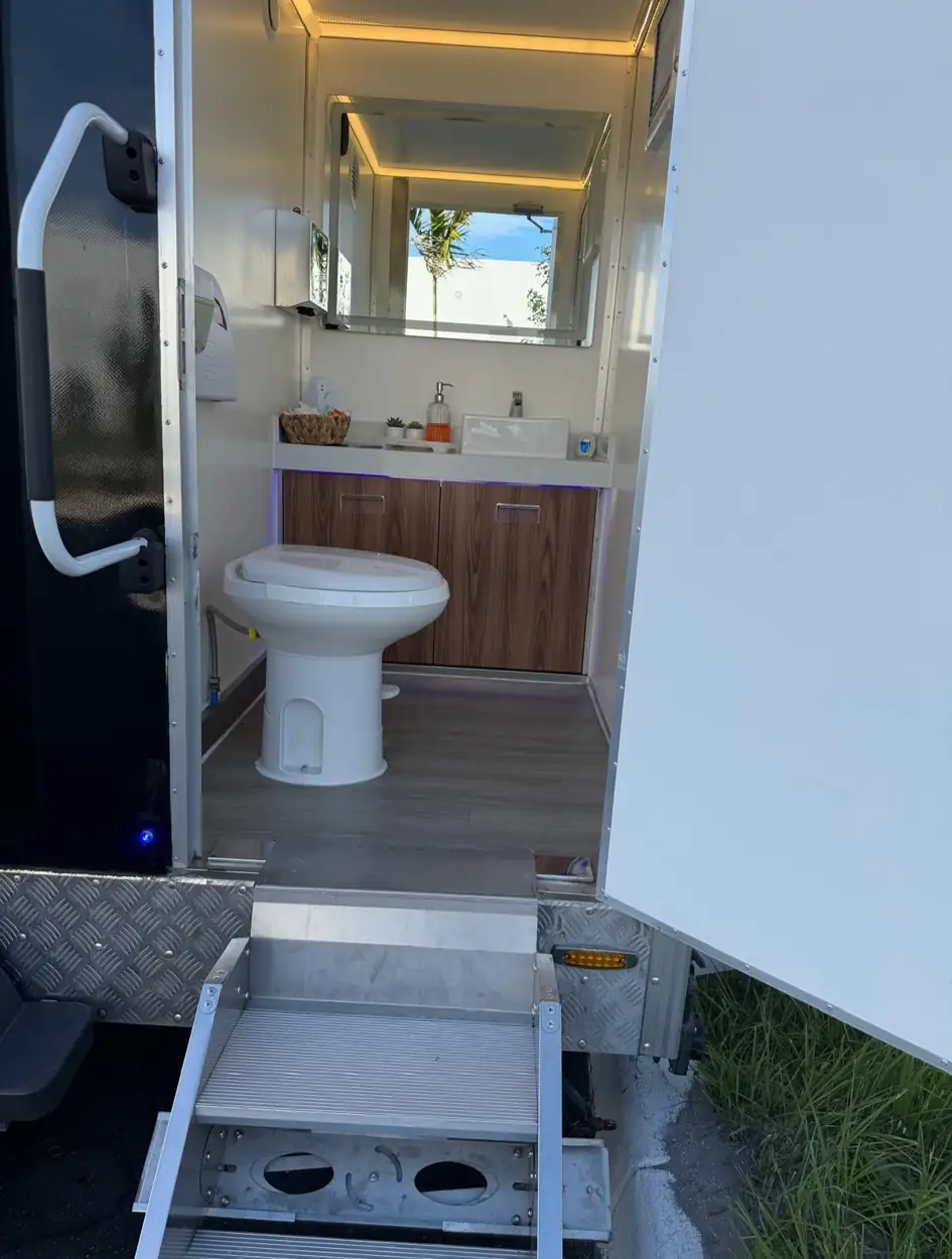 Restroom trailer toilet with handrail by the door