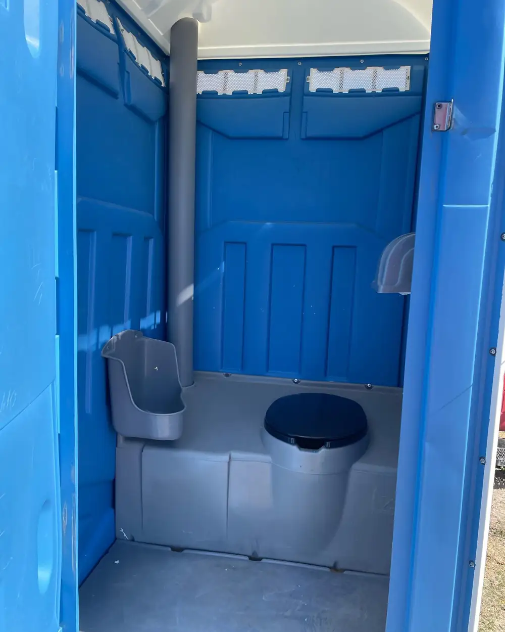 Inside a standard porta potty with seat and urinal
